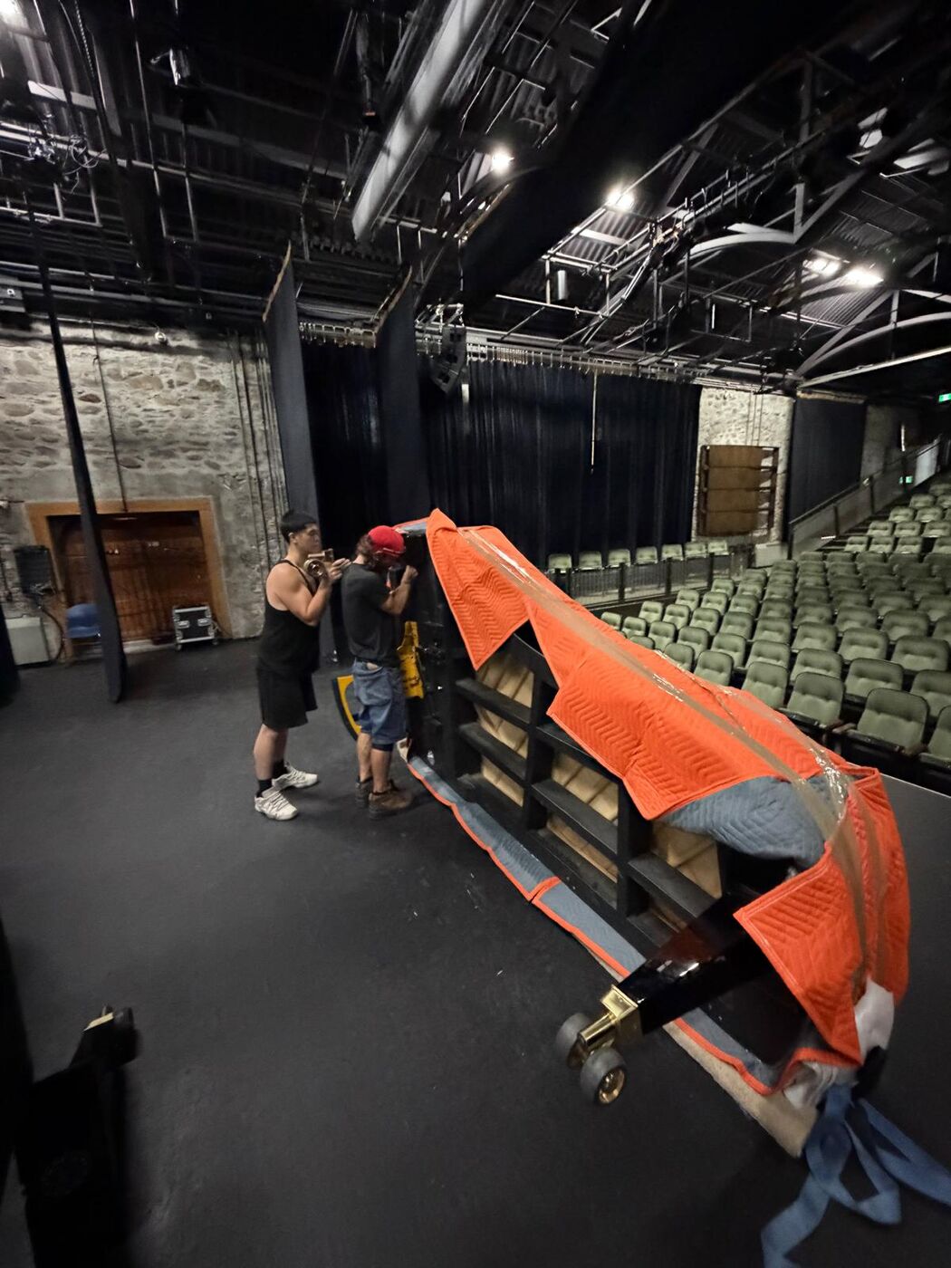 Piano à queue posé sur sa planche et recouvert de couvertures